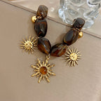 Bracelet bohème avec galets et pendentifs soleils effet oeil de tigre
